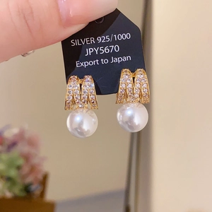 Macro detail of S925 silver earring featuring a crystal M motif and a lustrous round pearl