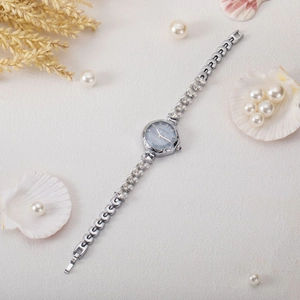 Detail of silver chain watch featuring pearl embellishments and a blue mother-of-pearl dial
