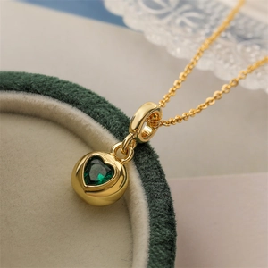 Gold-plated round necklace featuring a green heart-shaped zircon pendant on green velvet