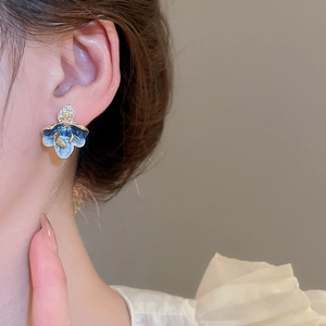 Detail einer blau-weißen Emaille-Blumenohrring mit Diamanten am Ohr eines Models