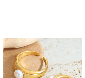 Detail of adjustable gold ring featuring a white pearl against textured stones
