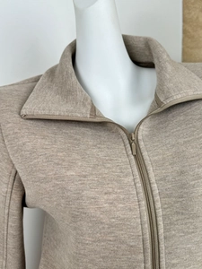 Close-up of the beige knit pullover with a stand collar and matching zipper detail
