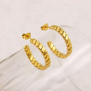 Close-up of golden twist rope hoop earrings displayed on a glass rim in French style