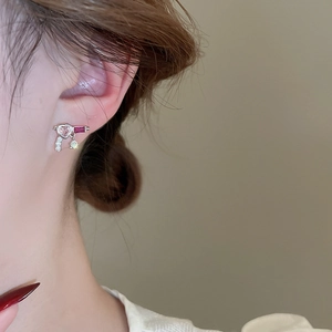 Close-up of a silver heart stud earring with pink gemstone and zircon on a model