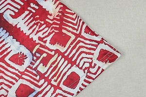 Macro detail of red geometric print fabric with high-quality stitching and fiber texture