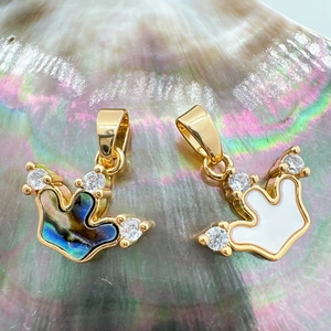 Macro shot of 18K gold plated crown pendants featuring abalone and white shell inlay