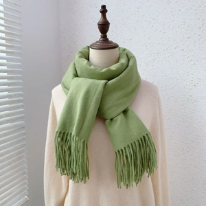 Detail of green faux cashmere scarf with tassels draped on a mannequin model