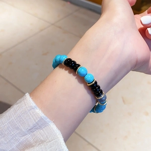 Close-up of blue turquoise and black onyx beaded bracelet with gold spacers on wrist