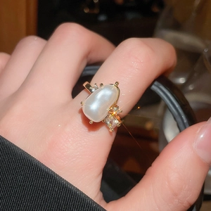 Detail of an irregular pearl ring with gold-plated setting and sparkling zircon accents