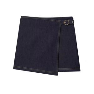 Détail de la jupe portefeuille en jean bleu foncé avec boucle dorée et surpiqûres