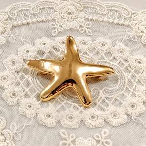 Polished gold starfish hair accessory made of stainless steel on white lace background