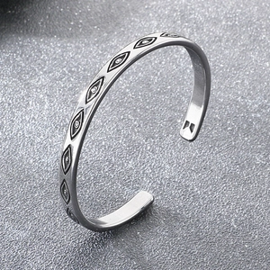Détail d'un bracelet jonc argenté en forme de C avec motifs géométriques gravés Evil Eye