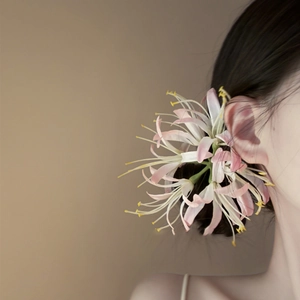 Detail of pink and white flower hair clip with yellow stamens worn on the side