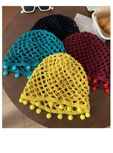 Flat lay of colorful knit bucket hats with beaded tassels in black green red and yellow
