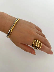 Close-up of stacked gold multi-layer ring and two-tone wave open cuff bracelet