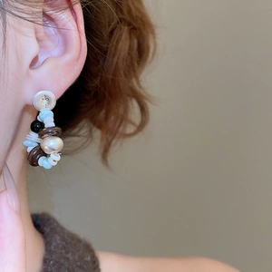 Detail of star-engraved silver stud with multi-color bead drop earrings on a model