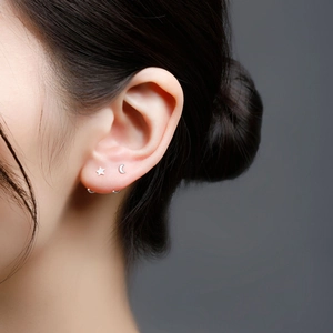 Macro close-up of sterling silver moon and star studs with minimalist hoop earrings