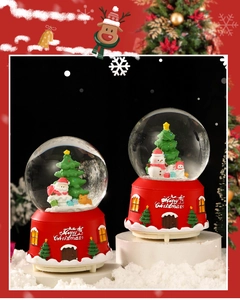 Close-up of a Christmas snow globe music box with Santa and snowman on red base