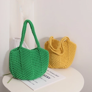 Handmade crochet cotton shoulder bag in green and yellow displayed on a stylish table