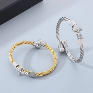 Detail of twisted cable cross bracelets in gold and silver finishes with a gift box