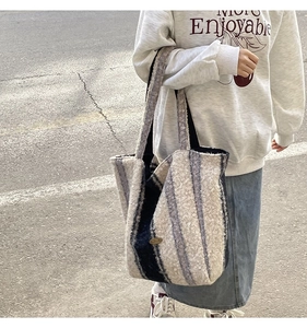 Close-up of thick striped wool tote bag with metal logo and wide shoulder strap