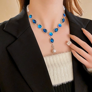 Dettaglio di una collana elegante con cristalli blu e perle indossata da una modella