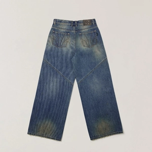 Close-up of vintage washed denim jeans with a textured cross pattern leather patch