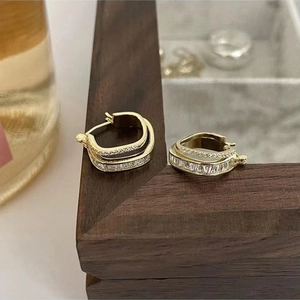 Detail von goldenen zweischichtigen Ohrringen mit funkelnden quadratischen Zirkonia