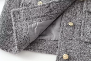 Close-up of textured grey boucle wool jacket with luxury embossed golden buttons