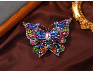 Macro detail of vintage butterfly brooch with colorful rhinestones on silk fabric