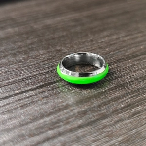 Detailed macro view of silver stainless steel ring with vibrant neon green luminous inlay