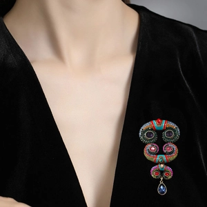 Vintage boho horn brooch with colorful rhinestones and blue teardrop pendant on velvet