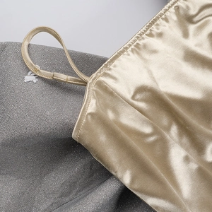 Détail macro du tissu satiné champagne avec des coutures fines sur la bretelle et le col