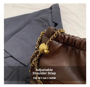 Makro-Detailaufnahme der braunen Ledertasche mit verstellbarer Goldkugel-Schulterkette