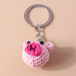 Close-up of pink handmade crochet pig keychain with soft knitted texture and silver metal ring