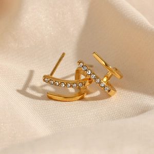 Macro shot of 18K gold-plated double-layer stud earrings with zircon on beige cloth