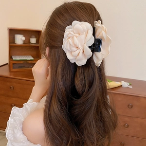 Close-up of a model wearing a beige silk flower hair claw clip in a French retro style