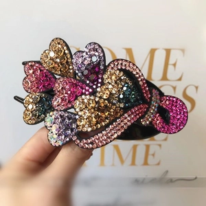 Macro detail of colorful crystal heart hair clip with sparkling rhinestones on black base