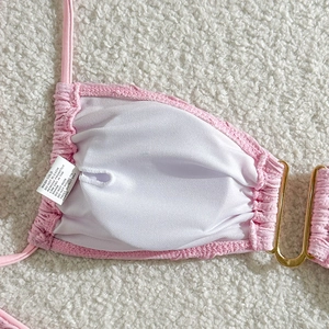 Detail of pink ribbed bikini fabric with white mesh lining and gold metal buckle