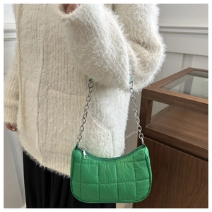 Détail du petit sac matelassé vert fluo avec bandoulière chaîne argentée sur manteau