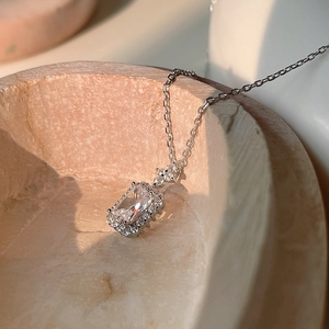 Close-up of S925 sterling silver necklace with emerald-cut zircon pendant on marble