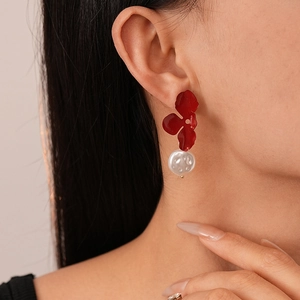 Elegant model side view wearing red flower petal earrings with hanging pearl drop accents
