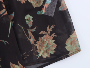 Detailaufnahme des Blumendrucks auf schwarzem Chiffon mit eingenähtem Pflegeetikett