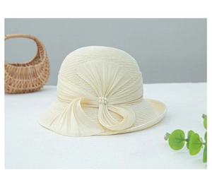 Détail d'un chapeau cloche en paille élégant avec nœud et perles délicates en blanc crème