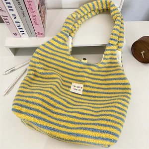 Detailansicht der flauschigen gelb-blau gestreiften Plüschtasche mit besticktem Etikett