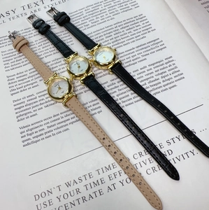 Three minimalist quartz watches with black and khaki leather straps on an open book
