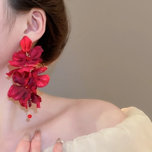 Close-up of red fabric flower earrings with long fringe tassels on model ear