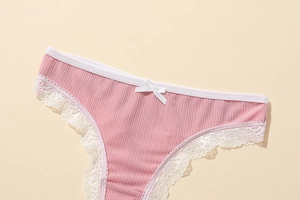 Détail du tissu côtelé rose avec bordure en dentelle blanche et petit nœud en soie