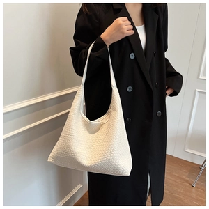 Detail of white woven hobo bag showing intricate faux leather texture and minimalist design