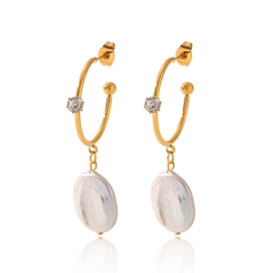 Détail de boucles d'oreilles perles baroques dorées avec zircon et texture